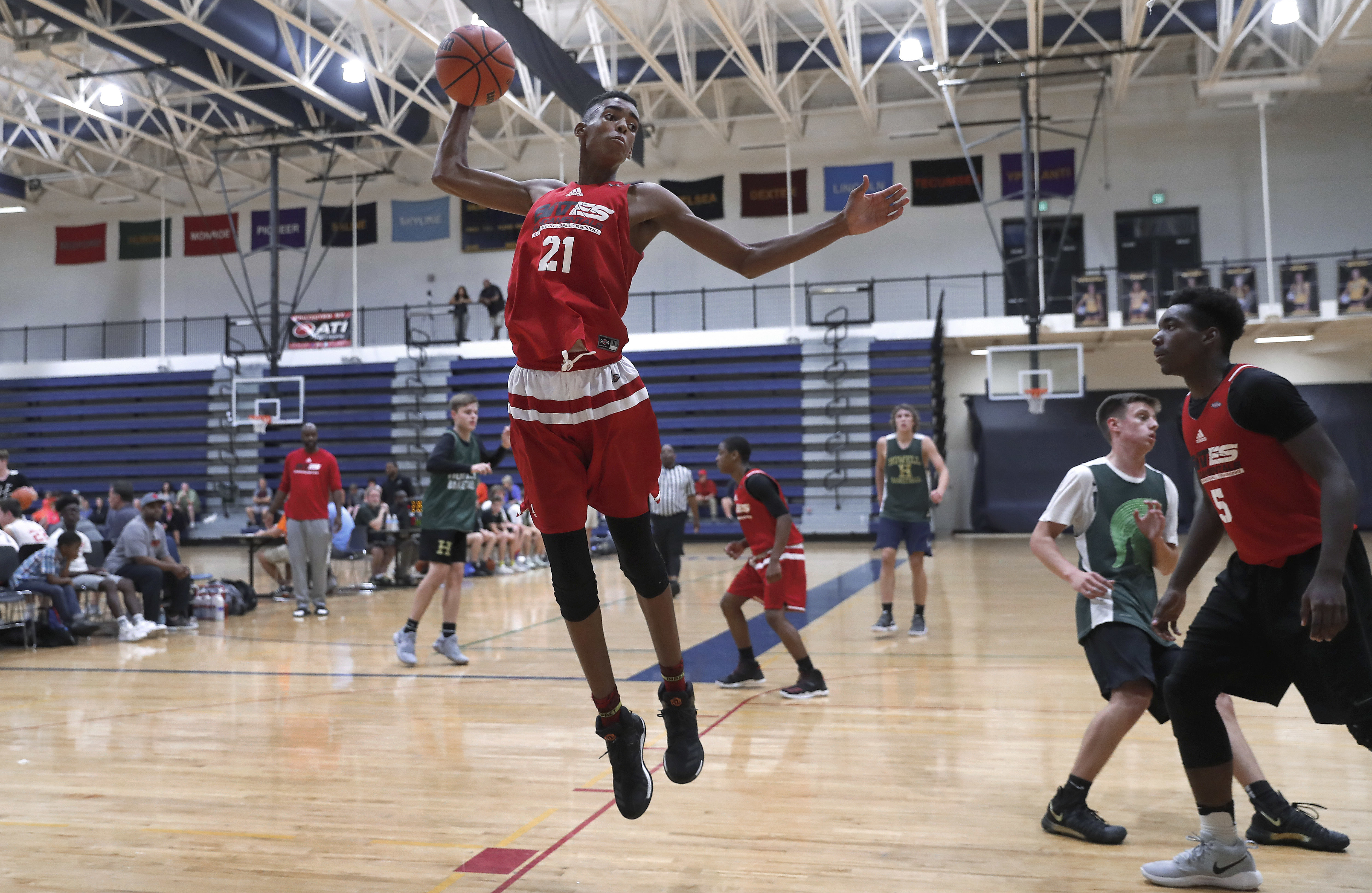 In this Oct. 8, 2017, photo, Emoni Bates pulls down a rebound against Howell High School during a fall league basketball game in Saline, Mich. The 13-year-old, 6-foot-7 basketball player is one of the most coveted young players in hoops. (AP Photo/Paul Sancya)