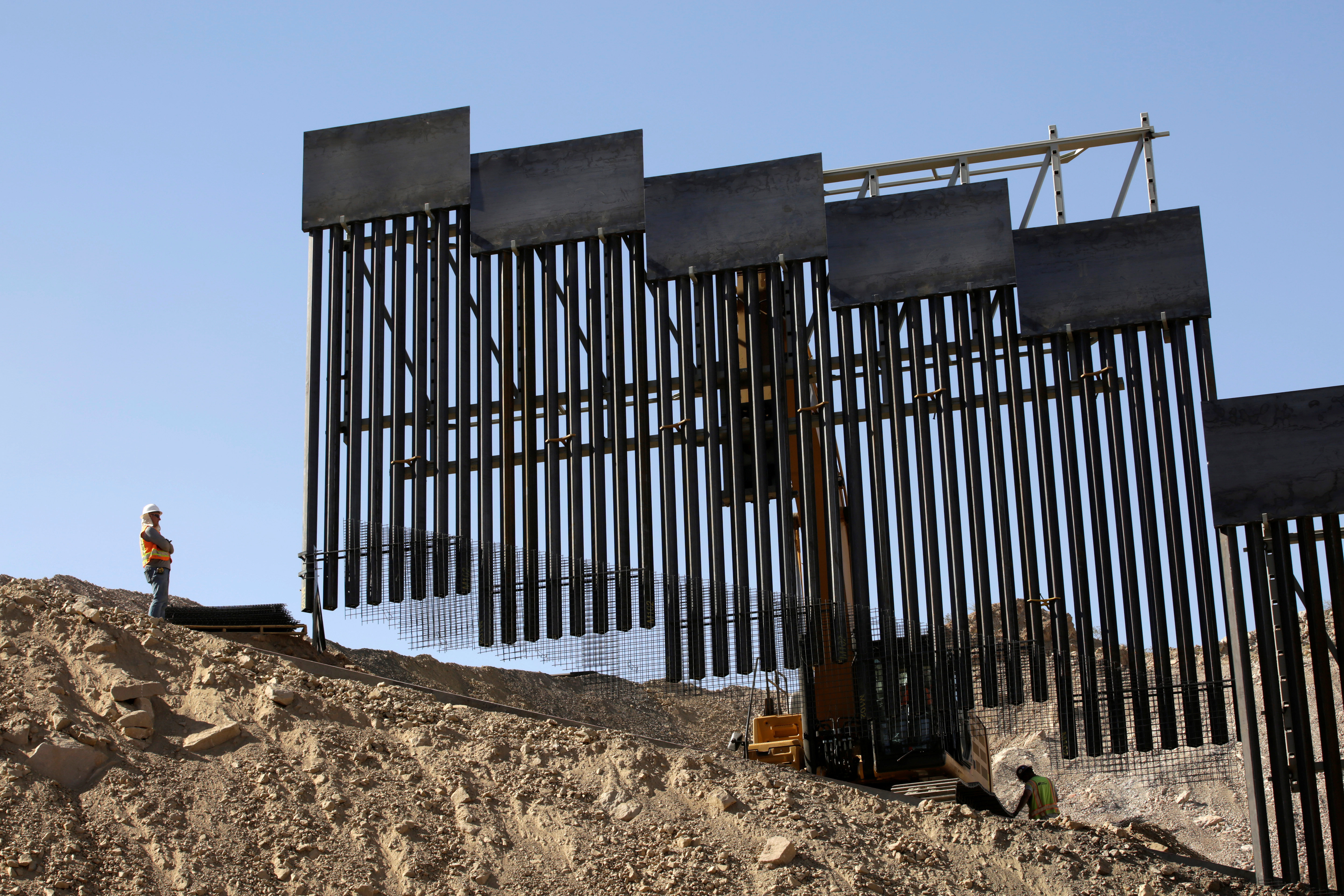 A construction crew works on a private border wall