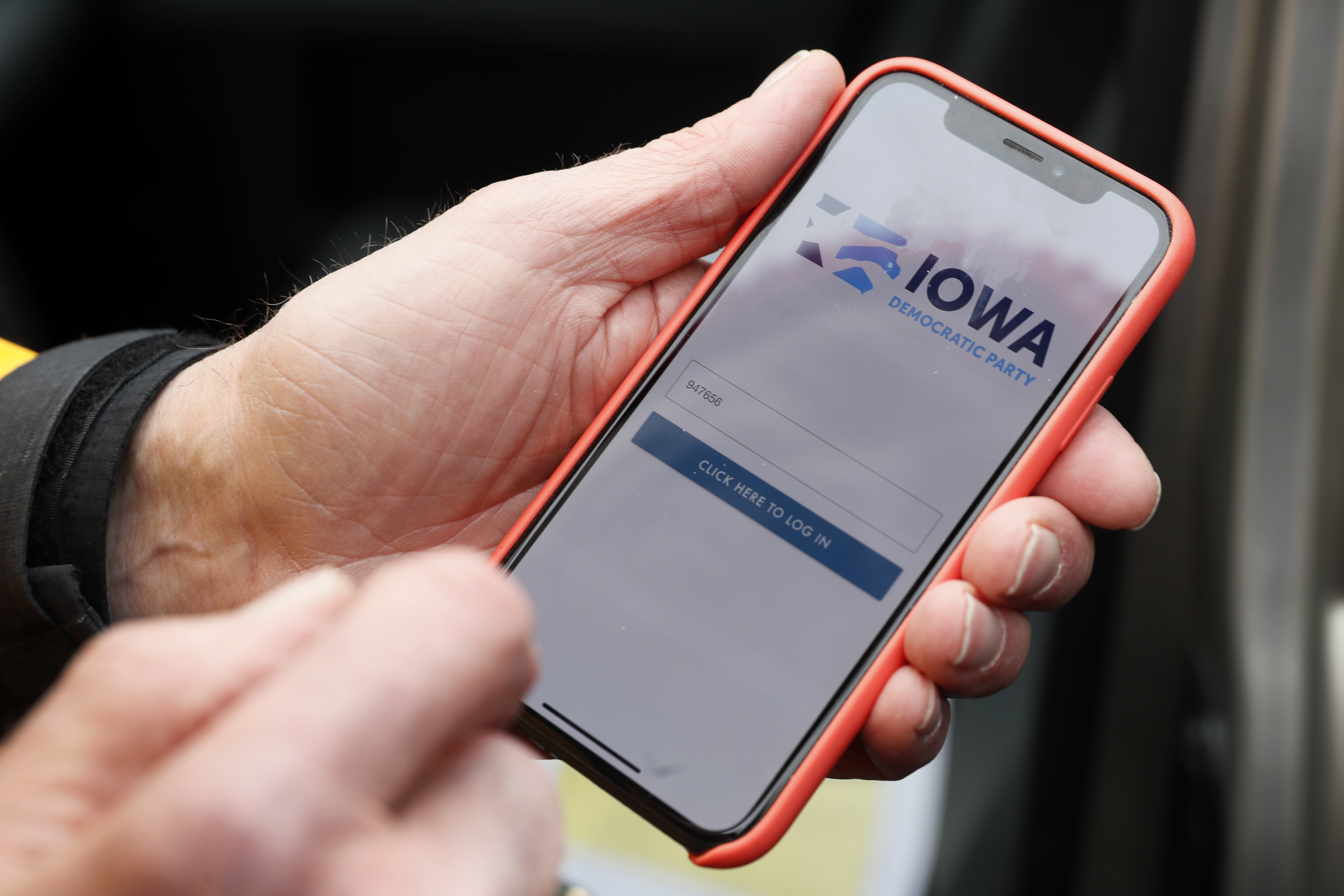 A precinct captain from Des Moines, Iowa, holds his iPhone that shows the Iowa Democratic Party's caucus reporting app in Nov. 2019. (Charlie Neibergall/AP)