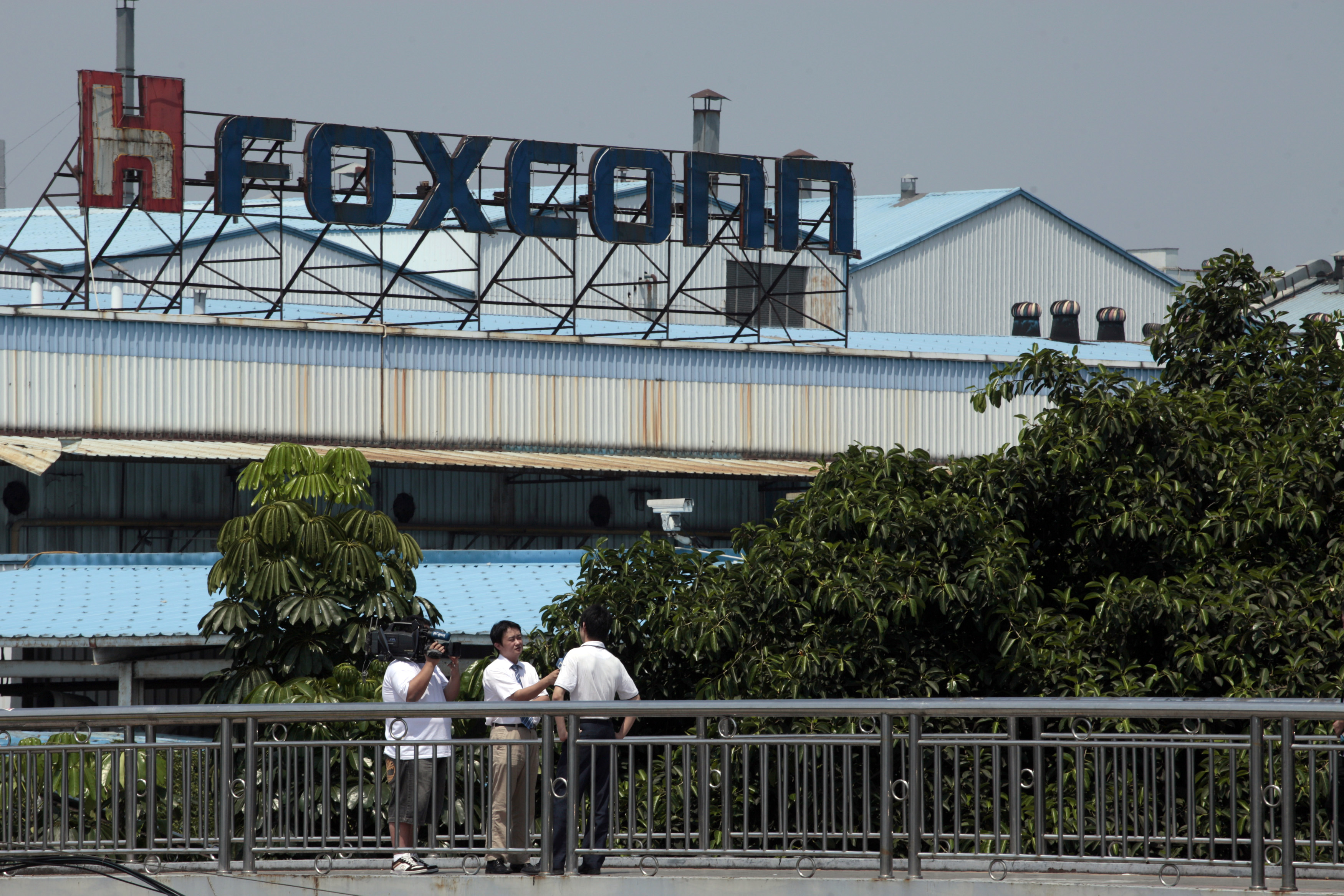 Employees of Foxconn speak to reporters outside one of the tech firm's factories in the southern Chinese city of Shenzhen May 25, 2010. An employee of Foxconn died early on Tuesday after falling from a building in southern city of Shenzhen, state media reported, the ninth such death at the firm's manufacturing hub this year. REUTERS/Tyrone Siu (CHINA - Tags: BUSINESS EMPLOYMENT SCI TECH DISASTER)