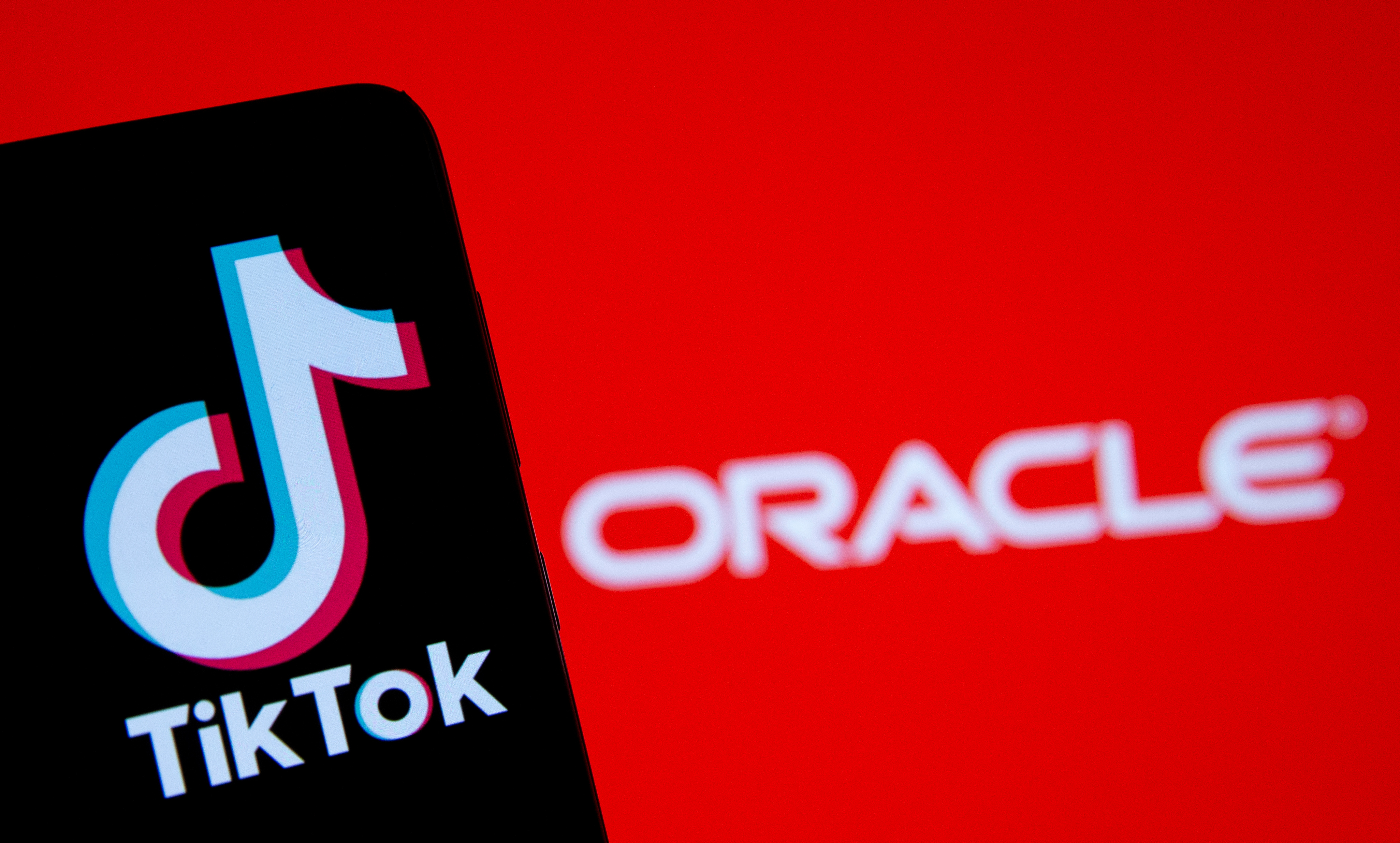 A smartphone with the Tik Tok logo is seen in front of a displayed Oracle logo in this illustration taken, Septemeber 14, 2020. REUTERS/Dado Ruvic/Illustration