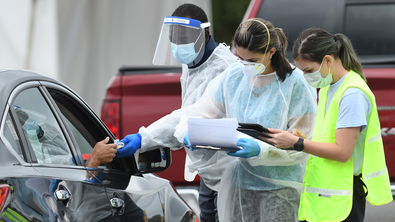 Healthcare workers greet the temporary drive-through COVID-19 test site at East Orange District Park on October 1, 2020 in Orlando, Florida.  (Photo by Paul Hansie / Freight by Getty Images)