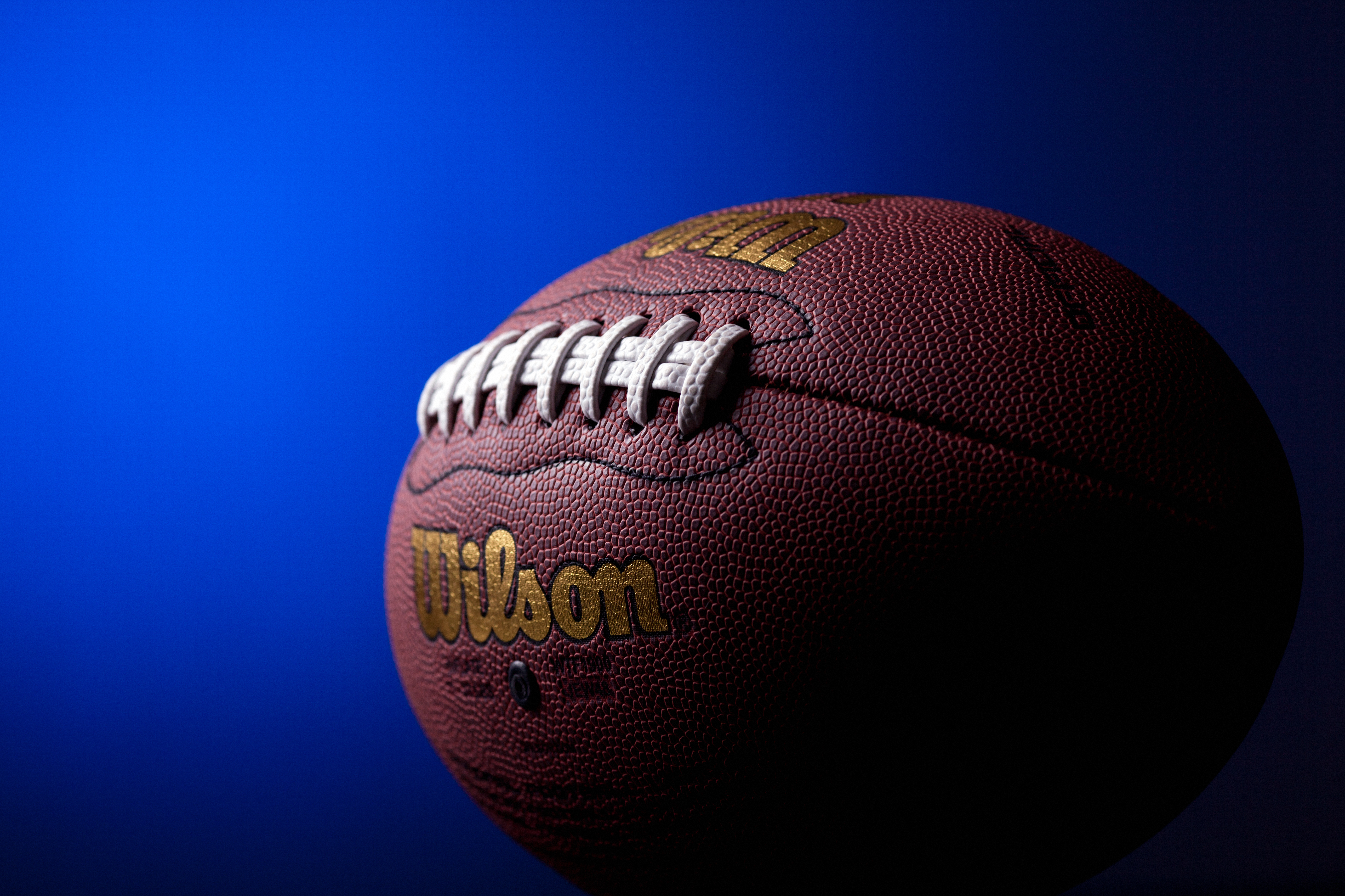 "Kragujevac, Serbia - November 17, 2012: Wilson Composite leather replica of the official NFL American football ball. Photo taken in studio, with blue gradient in the background"