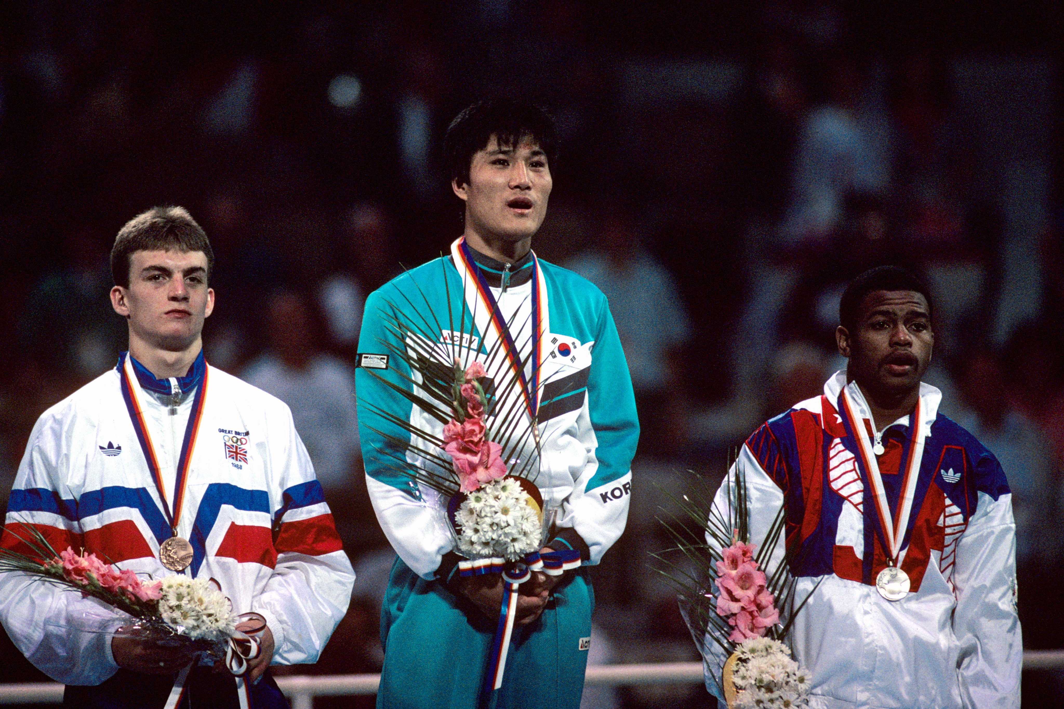 The medallists stand atop the dais as the winner's national anthem is played: (l-r) Great Britain's Richie Woodhall (bronze), Korea's Park Si-Hun (gold), USA's Roy Jones (silver)  (Photo by S&G/PA Images via Getty Images)
