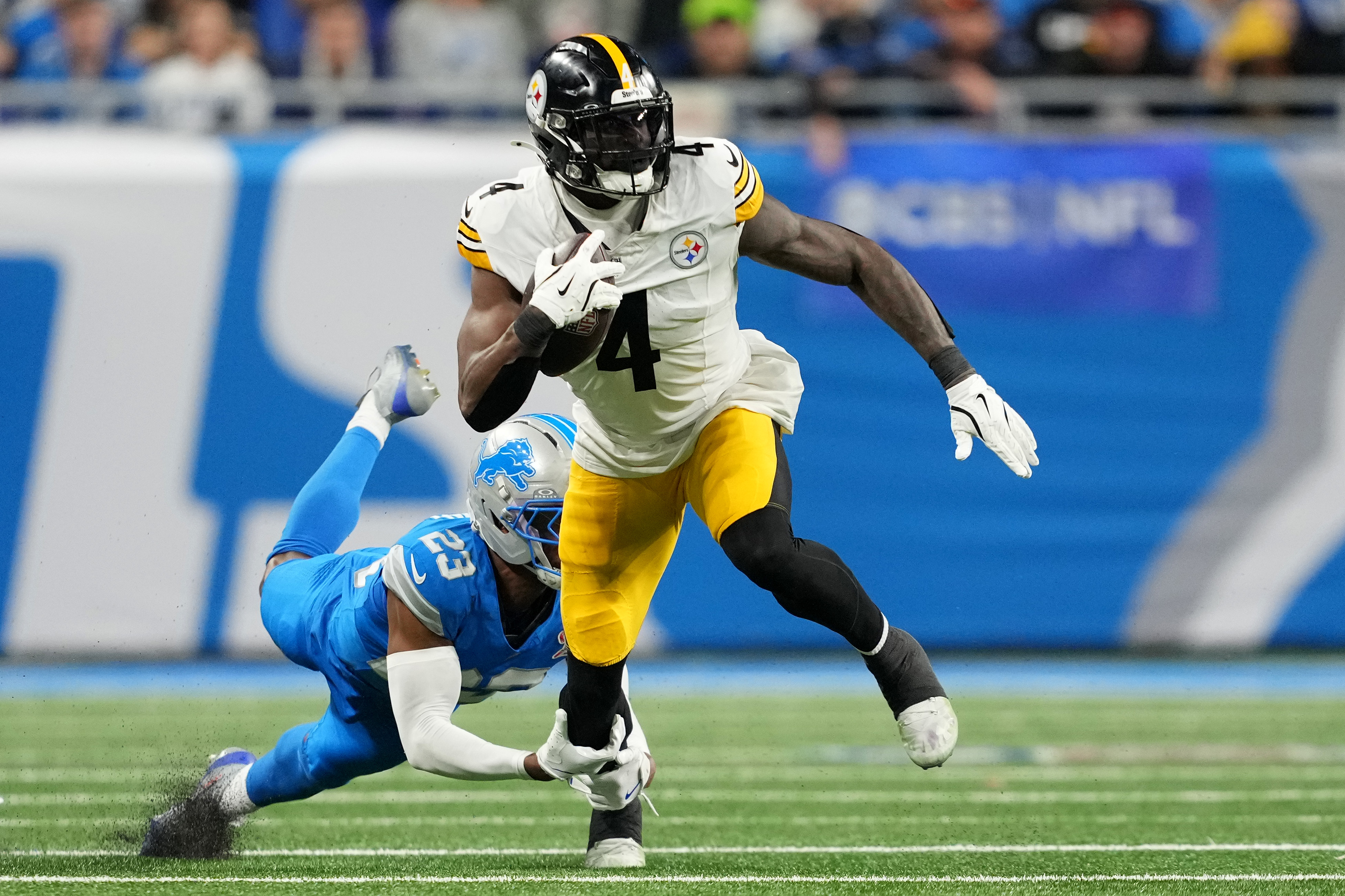 DETROIT, MICHIGAN - DECEMBER 21: DK Metcalf #4 of the Pittsburgh Steelers runs with the ball as Thomas Harper #12 of the Detroit Lions attempts a tackle during the third quarter at Ford Field on December 21, 2025 in Detroit, Michigan. (Photo by Nic Antaya/Getty Images)