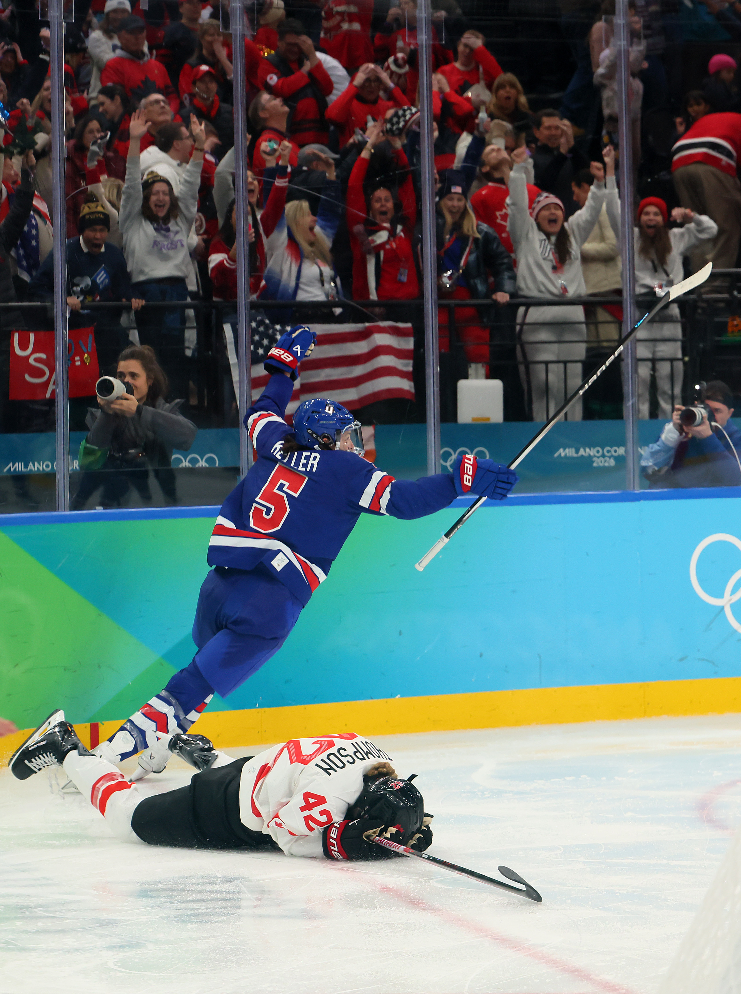 MILAN, ITALY - FEBRUARY 19: Megan Keller #5 of Team United States celebrates after scoring the game-winning goal in overtime as Claire Thompson #42 of Team Canada reacts during the Women's Gold Medal match between the United States and Canada on day 13 of the Milano Cortina 2026 Winter Olympic games at Milano Santagiulia Ice Hockey Arena on February 19, 2026 in Milan, Italy. (Photo by Bruce Bennett/Getty Images)