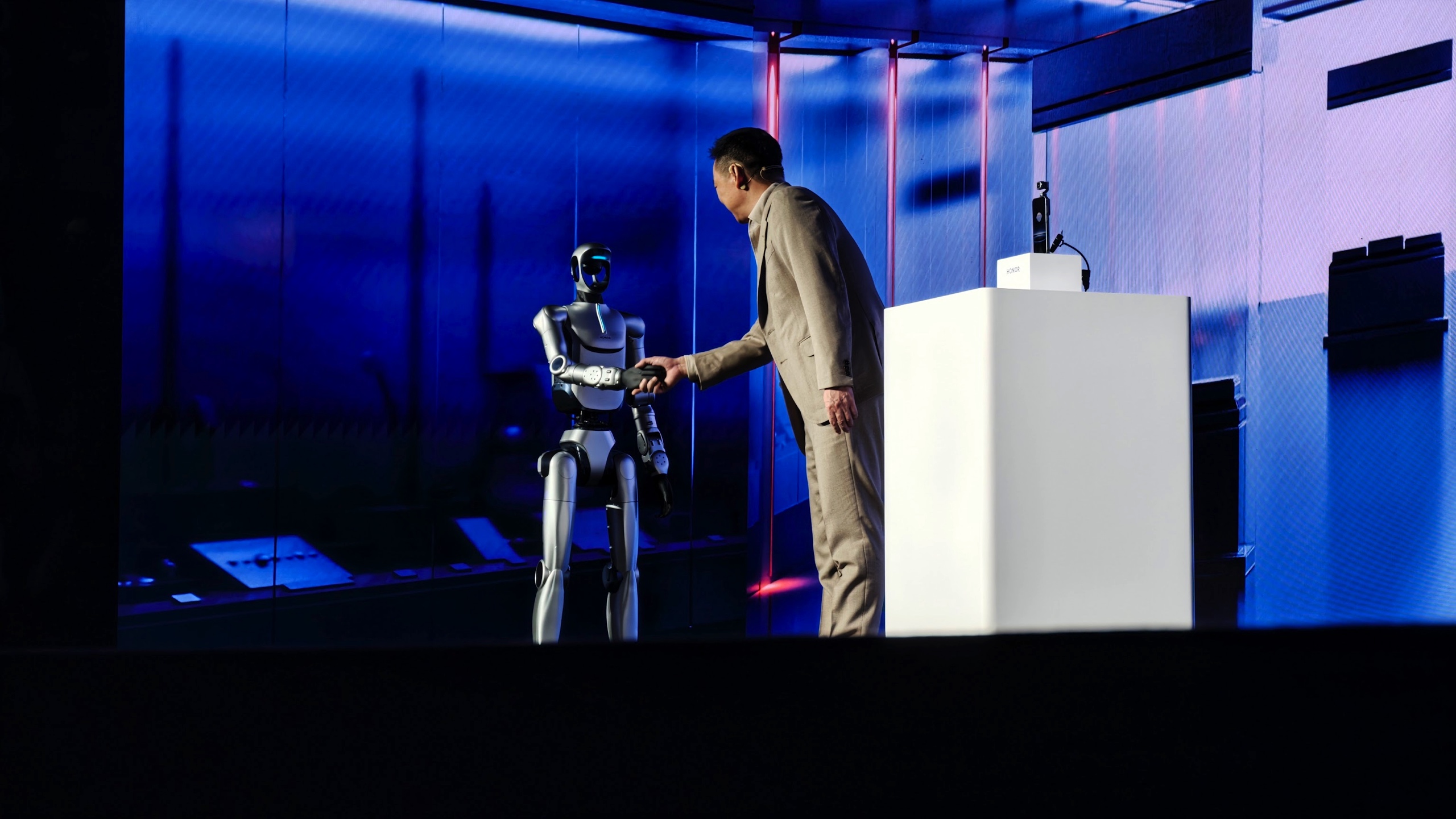 Honor's humanoid robot is shown shaking hands with CEO James Li on stage at MWC